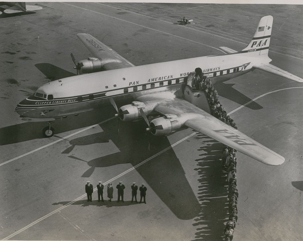 1950s Crew and customers line up on the ramp next to a Pan Am DC6 Clipper.